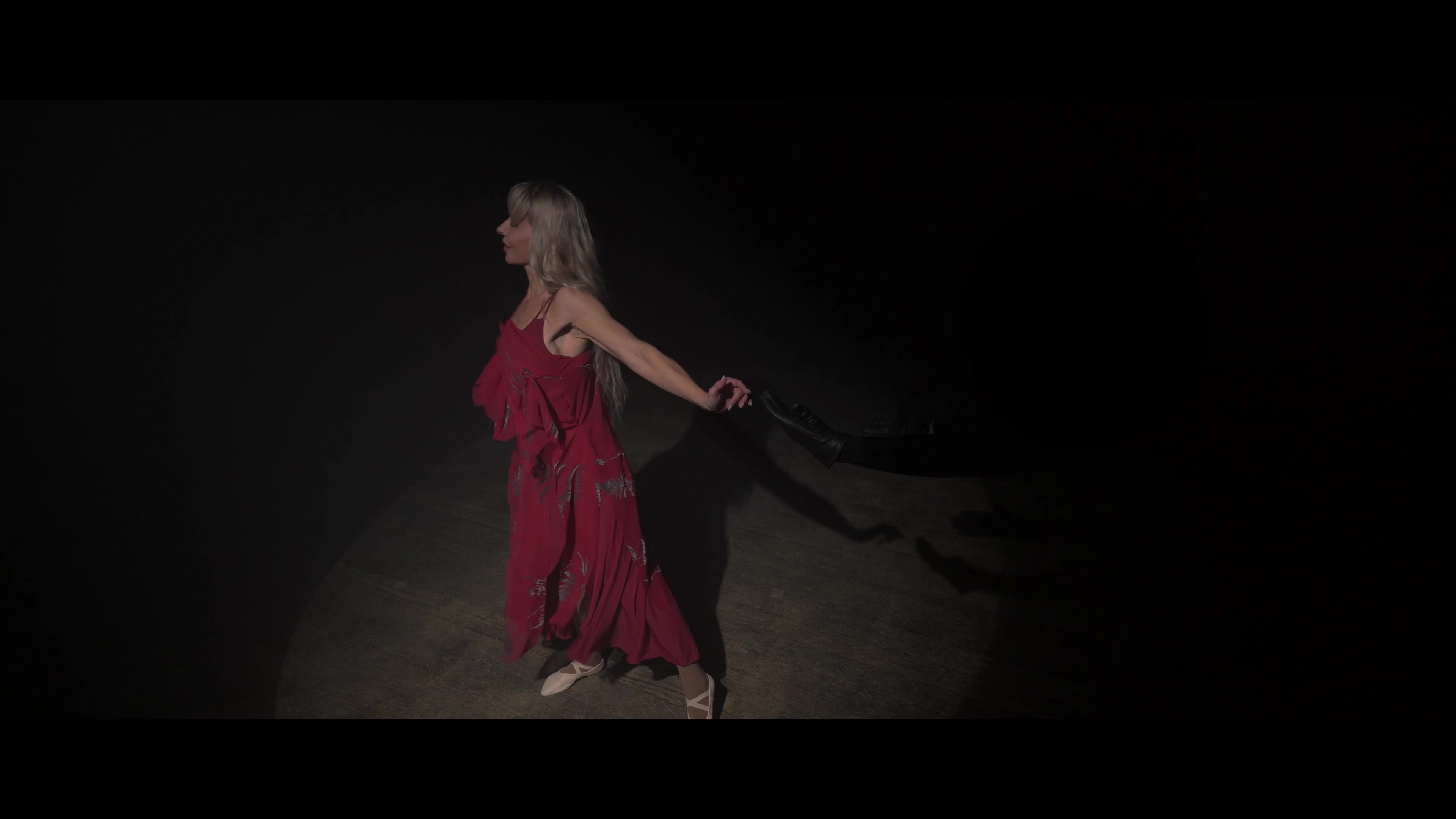 Julia Romanovich in a red dress holding black shoes
